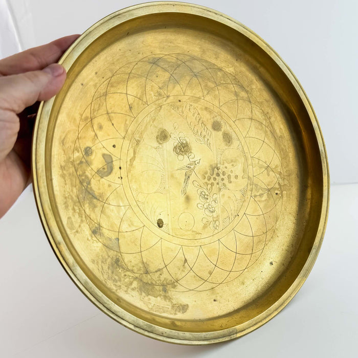 Angled view of vintage engraved brass tray swith hand for scale