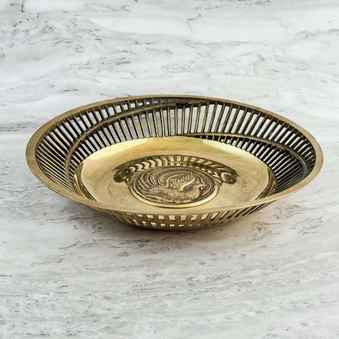 Three-quarter view of brass bowl with pierced sides and exotic bird center medalion