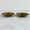 Pair of vintage engraved brass trinket dishes shown from the side on a light surface, revealing shallow bowl profile and wide engraved rim