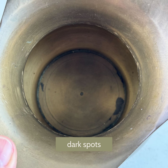 Interior view of brass pitcher showing aged surface variation and darker spots inside vessel