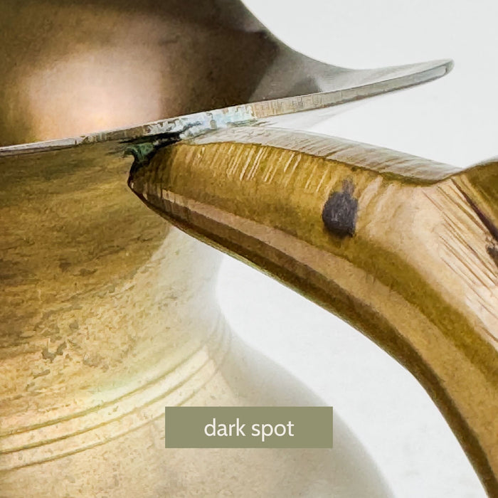 Close-up of brass pitcher handle showing dark spot 
