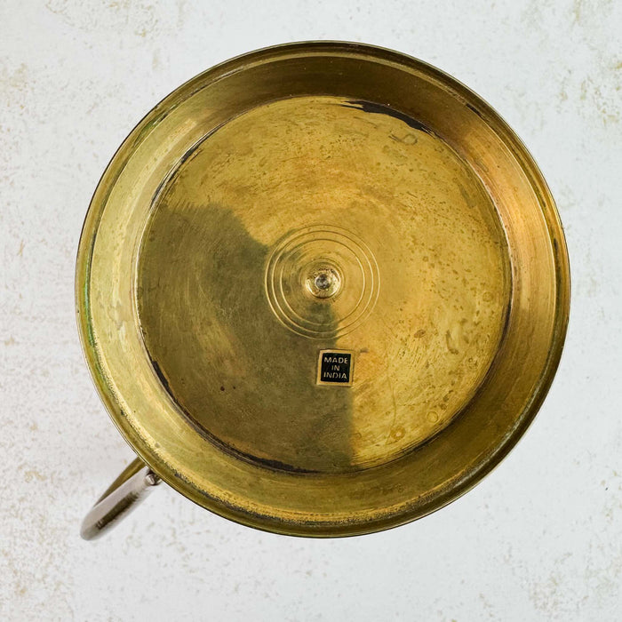 View of the bottom of the brass pitcher's pedestal showing the Made in India sticker