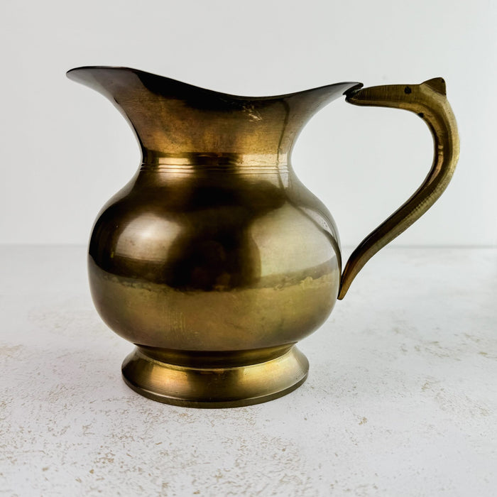 Full view of vintage brass pitcher with spout facing left