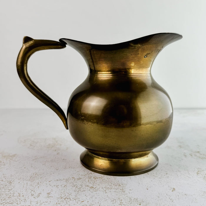 View of vintage brass pitcher with spout facing right