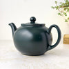 Three-quarter view of matte black Pristine teapot showing its rounded body, fitted lid, curved spout, and loop handle