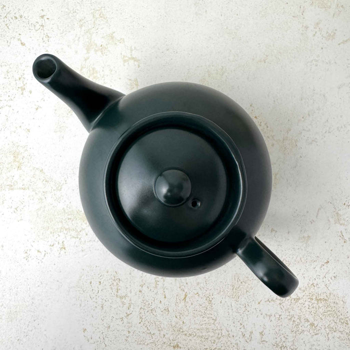 Overhead view of matte black teapot showing the round lid, ball finial, small vent hole, spout, and handle