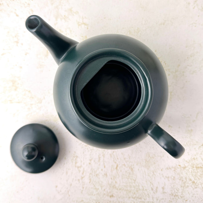 Overhead view inside the matte black teapot with the lid removed and placed alongside