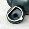 Close-up of the underside of the teapot lid showing its unglazed rim and black glazed interior