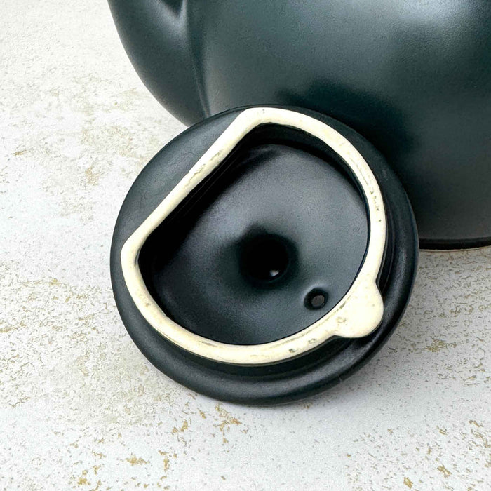 Close-up of the underside of the teapot lid showing its unglazed rim and black glazed interior