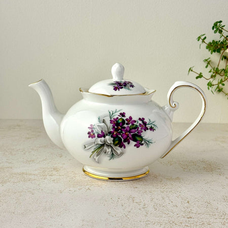 Vintage Royal Grafton bone china teapot with purple violets, white bow design, gold trim, and curved handle