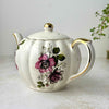 Vintage Gibsons Staffordshire England teapot, three-quarter view showing pink and black roses, gold-trimmed handle, and crazed ivory glaze.