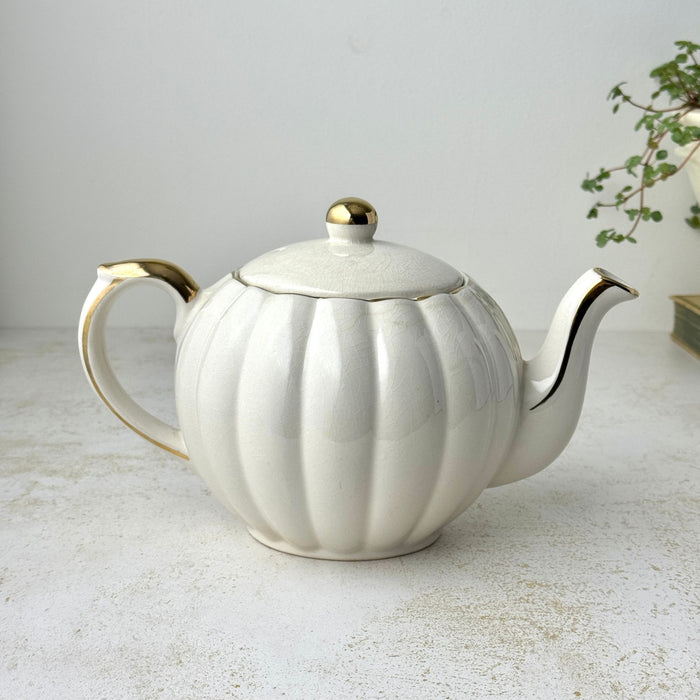 Vintage Gibsons Staffordshire England teapot, reverse view showing the fluted ivory body, curved handle, spout, and gold trim.
