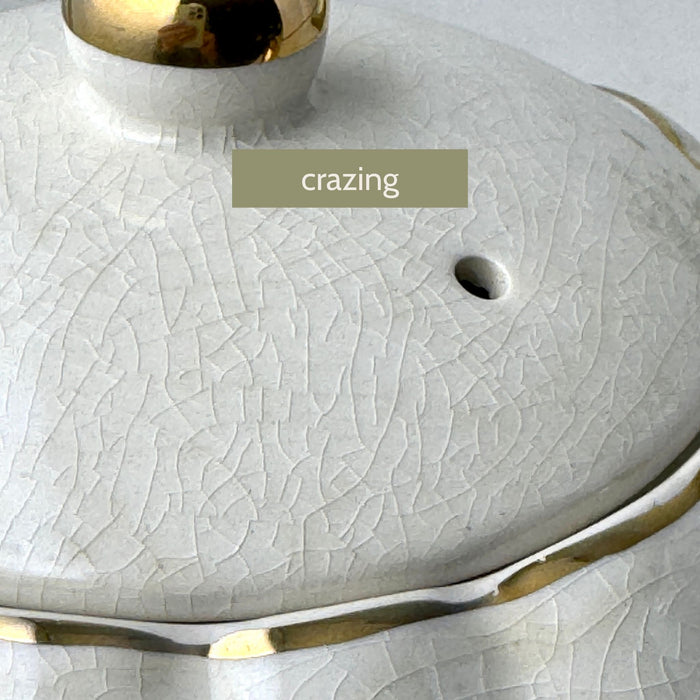 Vintage Gibsons Staffordshire England teapot lid, close-up showing age-related crazing in the ivory glaze.