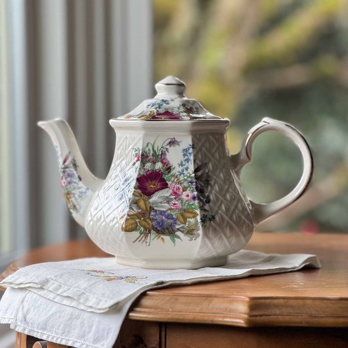 Vintage Sadler Windsor floral teapot on antique table with embroidered linen and soft garden window background