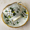 Front view of Royal Albert White Dogwood teacup resting on its side on matching saucer