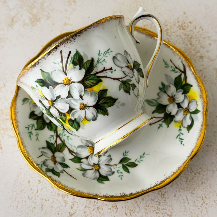 Front view of Royal Albert White Dogwood teacup resting on its side on matching saucer