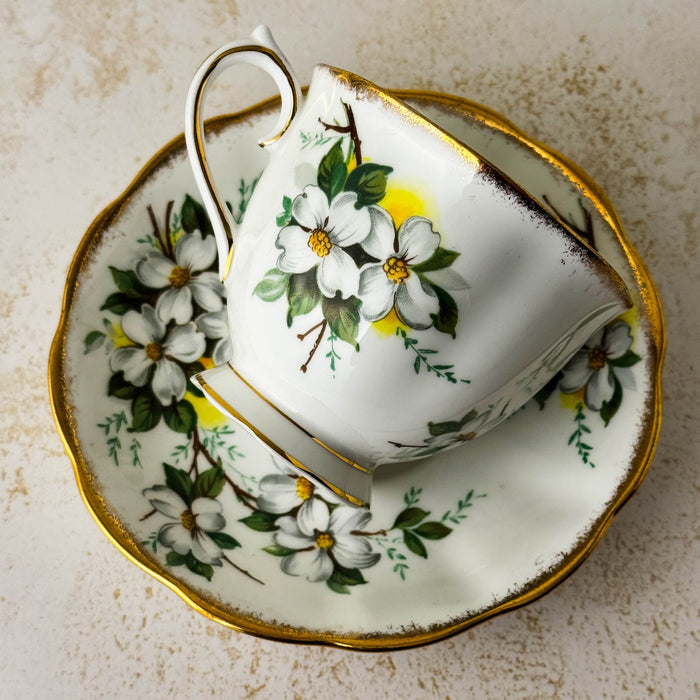 Back view of Royal Albert White Dogwood teacup resting on its side on matching saucer