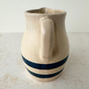 Handle side of vintage stoneware pitcher with cobalt blue bands