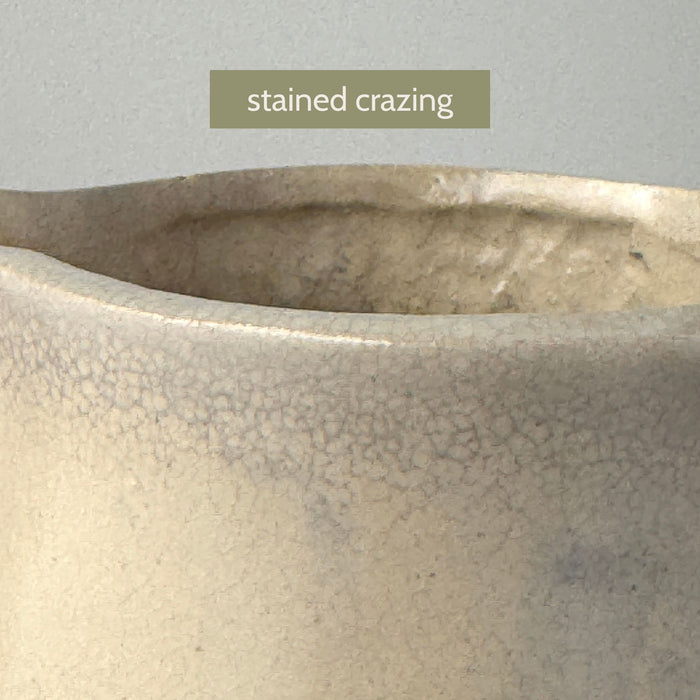 Close-up of the crazing and staining around the opening of the vintage stoneware pitcher and a label reading "stained crazing"