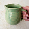Green Monmouth ribbed stoneware creamer held by a hand