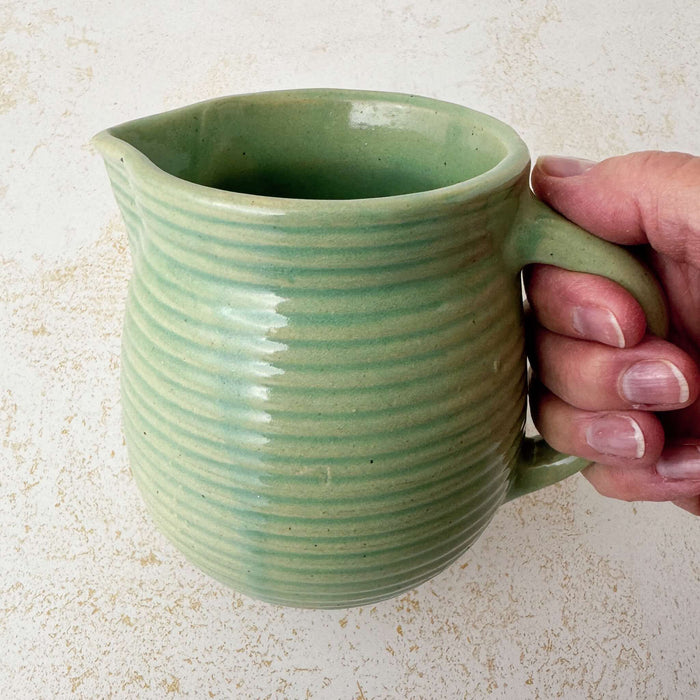 Green Monmouth ribbed stoneware creamer held by a hand
