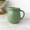 Small vintage Monmouth Pottery stoneware pitcher with ribbed body and soft green glaze styled with trailing plant