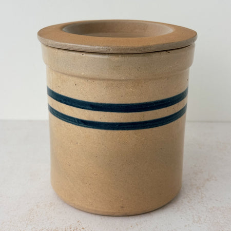 Side view of vintage lidded stoneware crock with blue bands