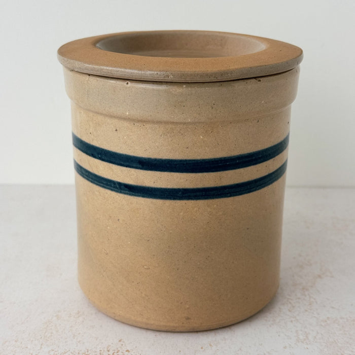 Side view of vintage lidded stoneware crock with blue bands