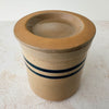 Three-quarter view of vintage lidded stoneware crock with blue bands