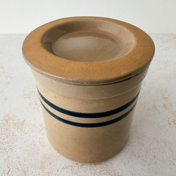 Three-quarter view of vintage lidded stoneware crock with blue bands