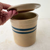 Hand lifting lid of vintage stoneware crock with cobalt bands