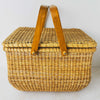 Side view of vintage lidded bamboo picnic basket with handles raised