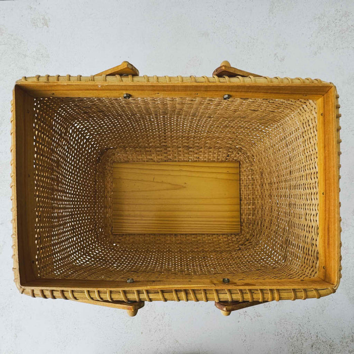 Top down view showing opening and interior of vintage lidded bamboo picnic basket with handles
