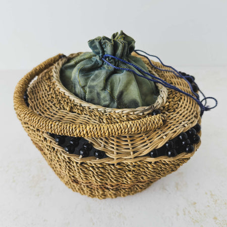 Three-quarter view of antique wicker vanity basket with beaded hexagonal form