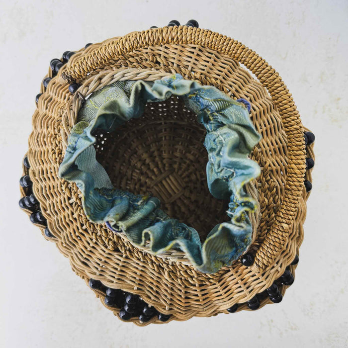 Top down view showing basket interior of antique wicker vanity basket with beaded hexagonal form