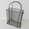 Three-quarter view of vintage handwired basket with twisted handles against a light background