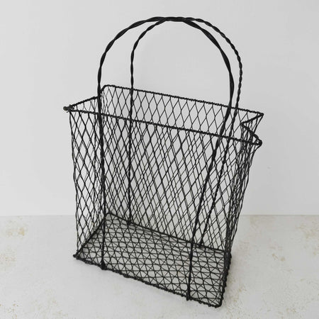 Three-quarter view of vintage handwired basket with twisted handles against a light background