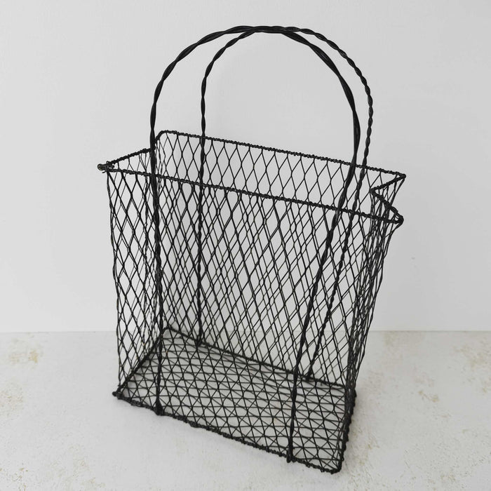 Three-quarter view of vintage handwired basket with twisted handles against a light background