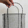 Hand holding twisted handle on vintage handwired wire basket