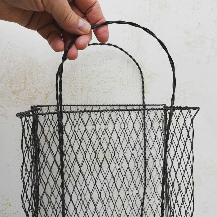 Hand holding twisted handle on vintage handwired wire basket