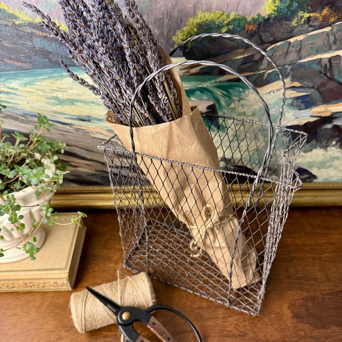 Vintage wire basket styled with kraft wrapped dried lavender, twine, and garden scissors on a wooden tabletop