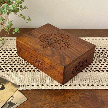 Vintage carved wood box with tree of life design and floral side carving, styled on a crochet runner with trailing plant and old photographs