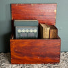 Antique primitive storage box with faux grain paint finish filled with vintage books against a muted green painted wall 