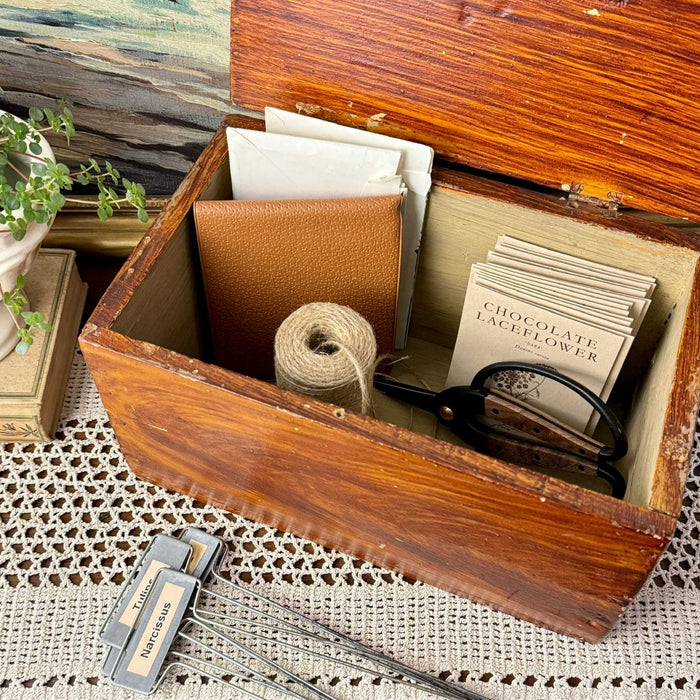 Antique faux grain painted wood storage box styled with garden supplies, twine, papers, and plant labels