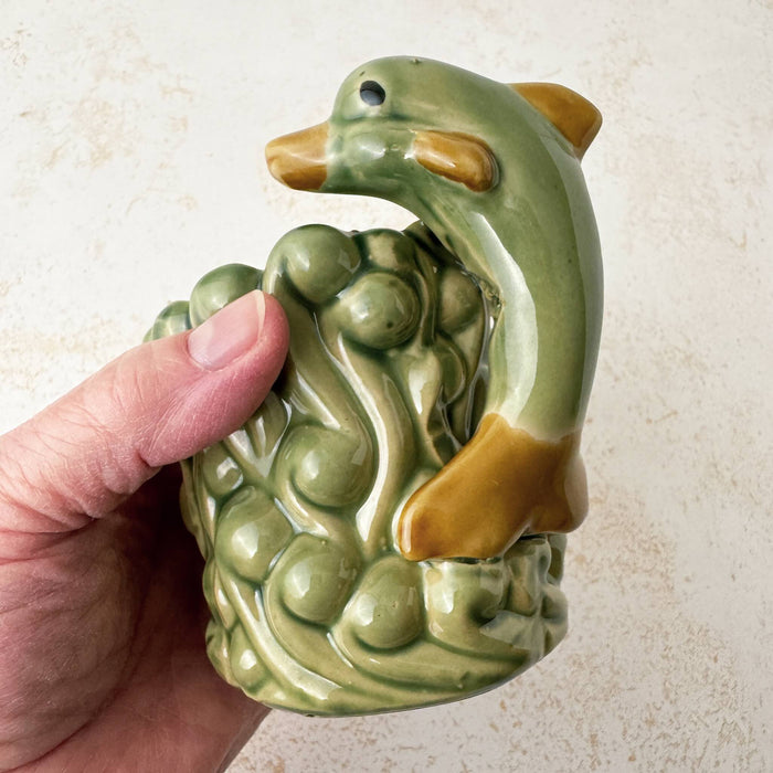 Hand holding vintage majolica dolphin cachepot