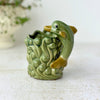 Vintage green ceramic planter with a figural dolphin arcing over sculpted waves and a scalloped rim