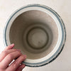 Top down view with fingers touching edge of Asian-style blue and gray ceramic cachepot