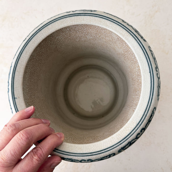 Top down view with fingers touching edge of Asian-style blue and gray ceramic cachepot