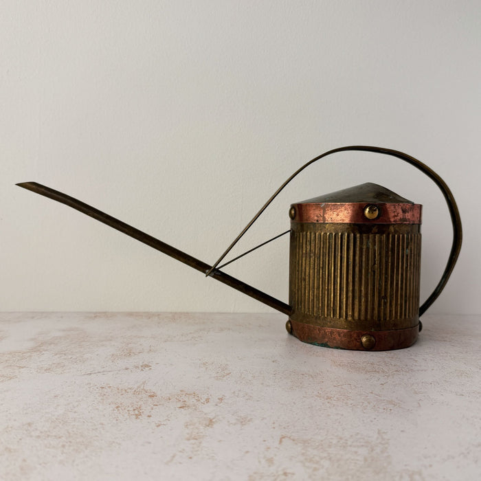 Front side view of vintage brass indoor watering can with copper accents