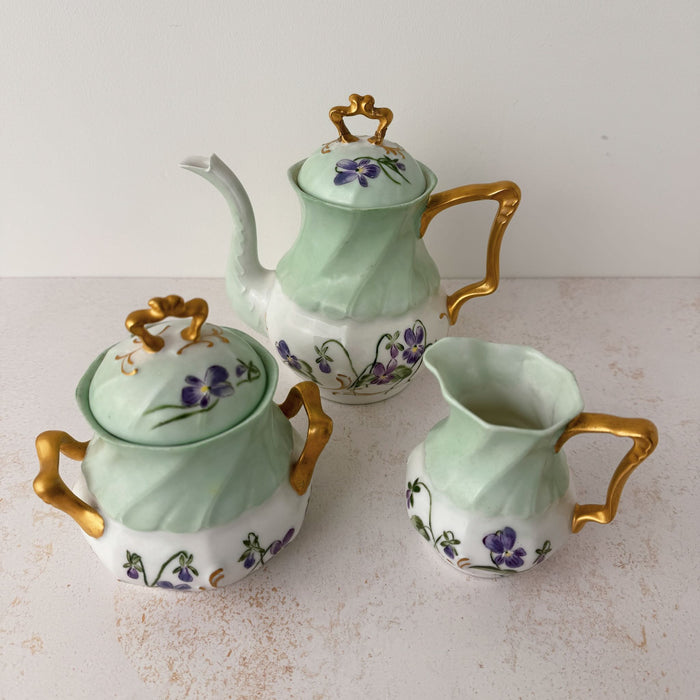 Angled down front view of Jean Pouyat Limoges violets tea set with teapot, sugar, creamer